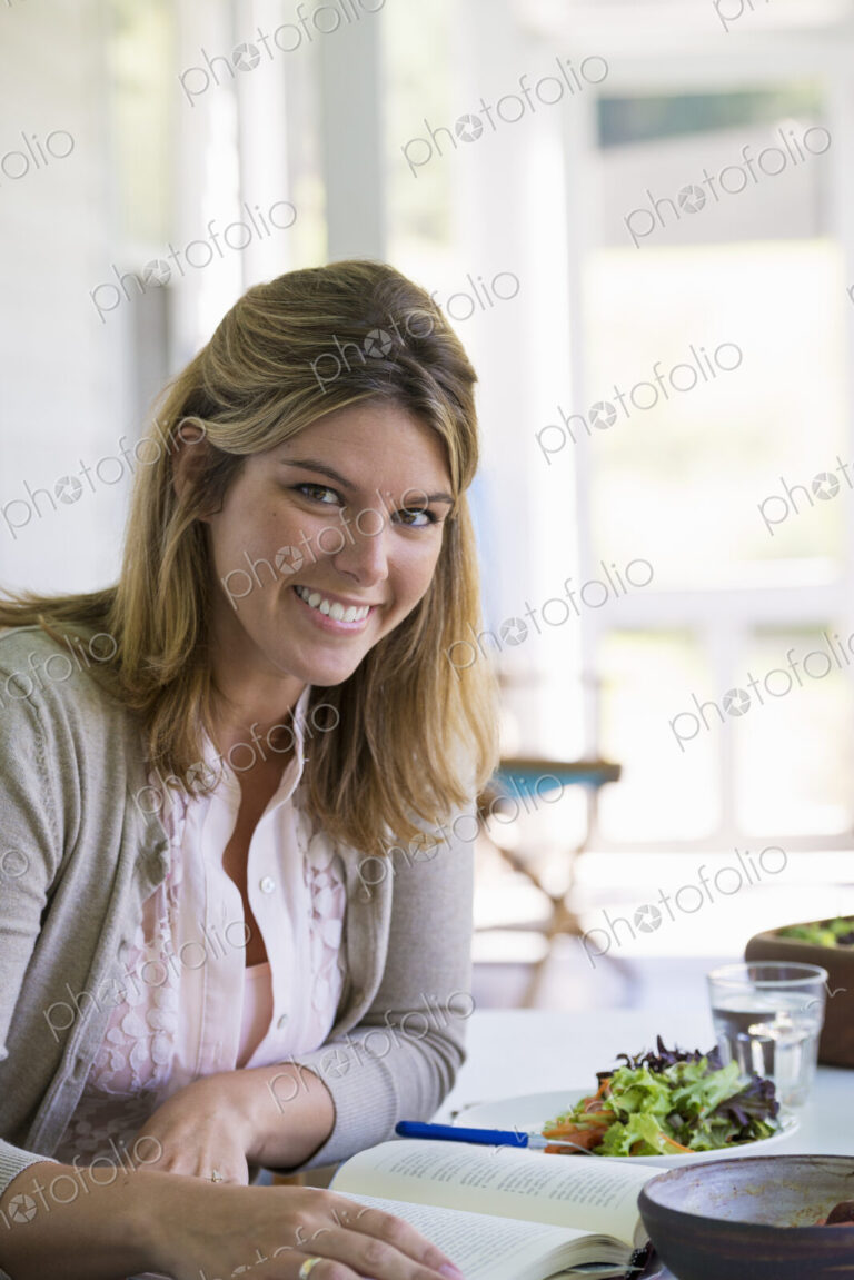 A woman sitting at a table reading a book.