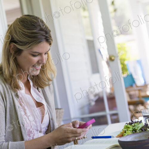 A woman sitting at a table using a smart phone. A woman sitting at a table using a smart phone.