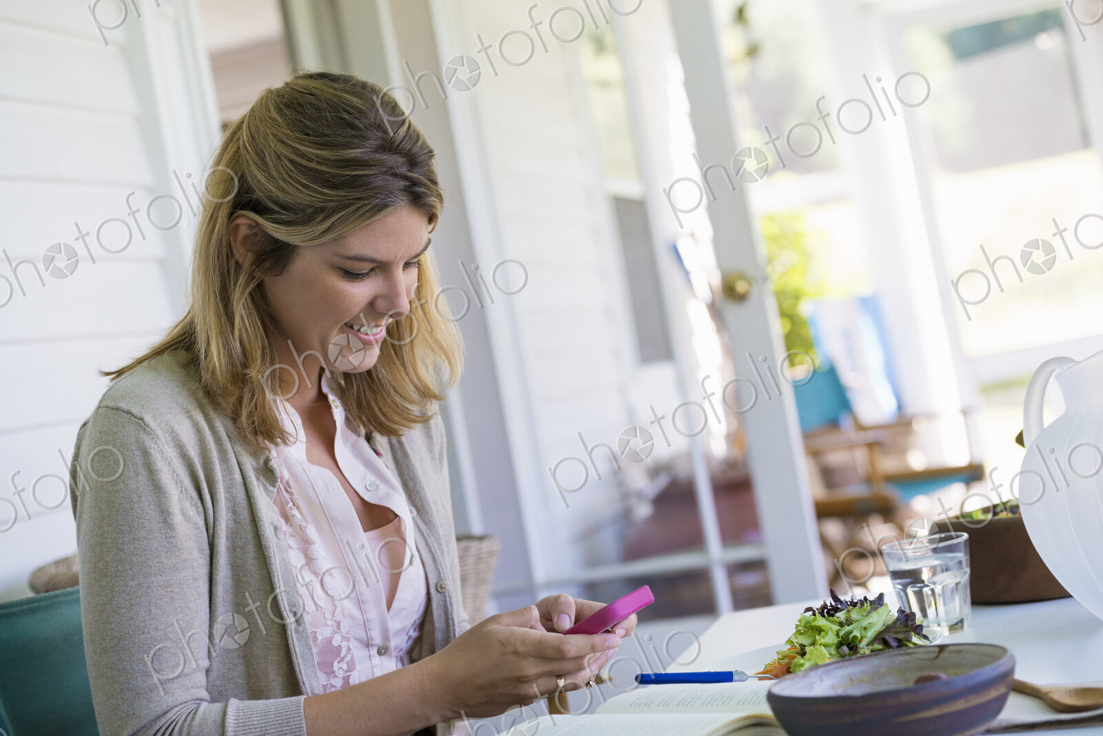 A woman sitting at a table using a smart phone.