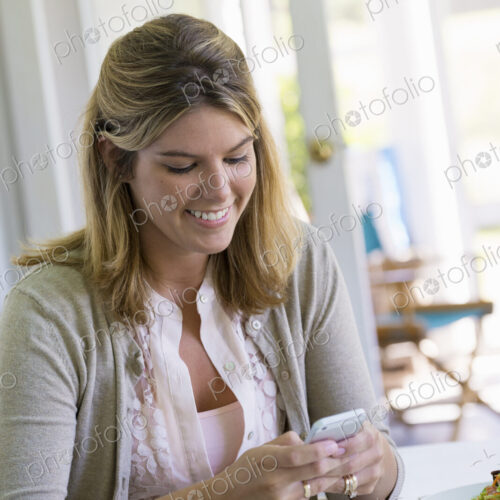 A woman sitting at a table using a smart phone. A woman sitting at a table using a smart phone.