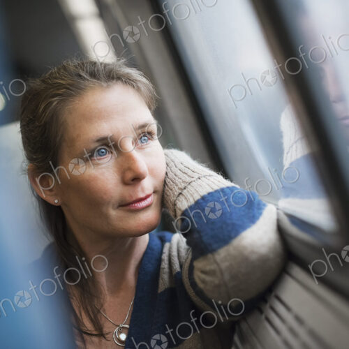 A woman sitting at a window seat in a train carriage, resting her head on her hand.… A woman sitting at a window seat in a train carriage, resting her head on her hand.…