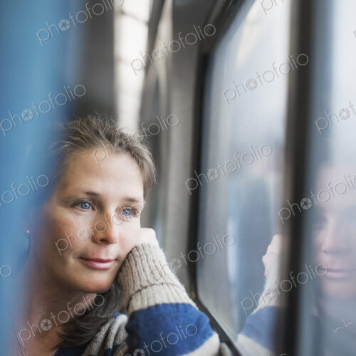 A woman sitting at a window seat in a train carriage, resting her head on her hand.… A woman sitting at a window seat in a train carriage, resting her head on her hand.…