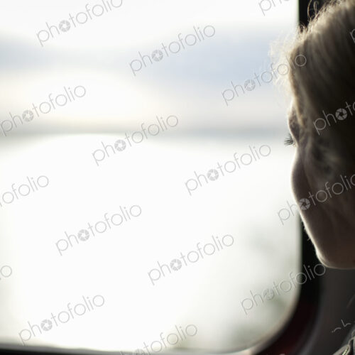 A woman sitting by a train window looking out at the view.