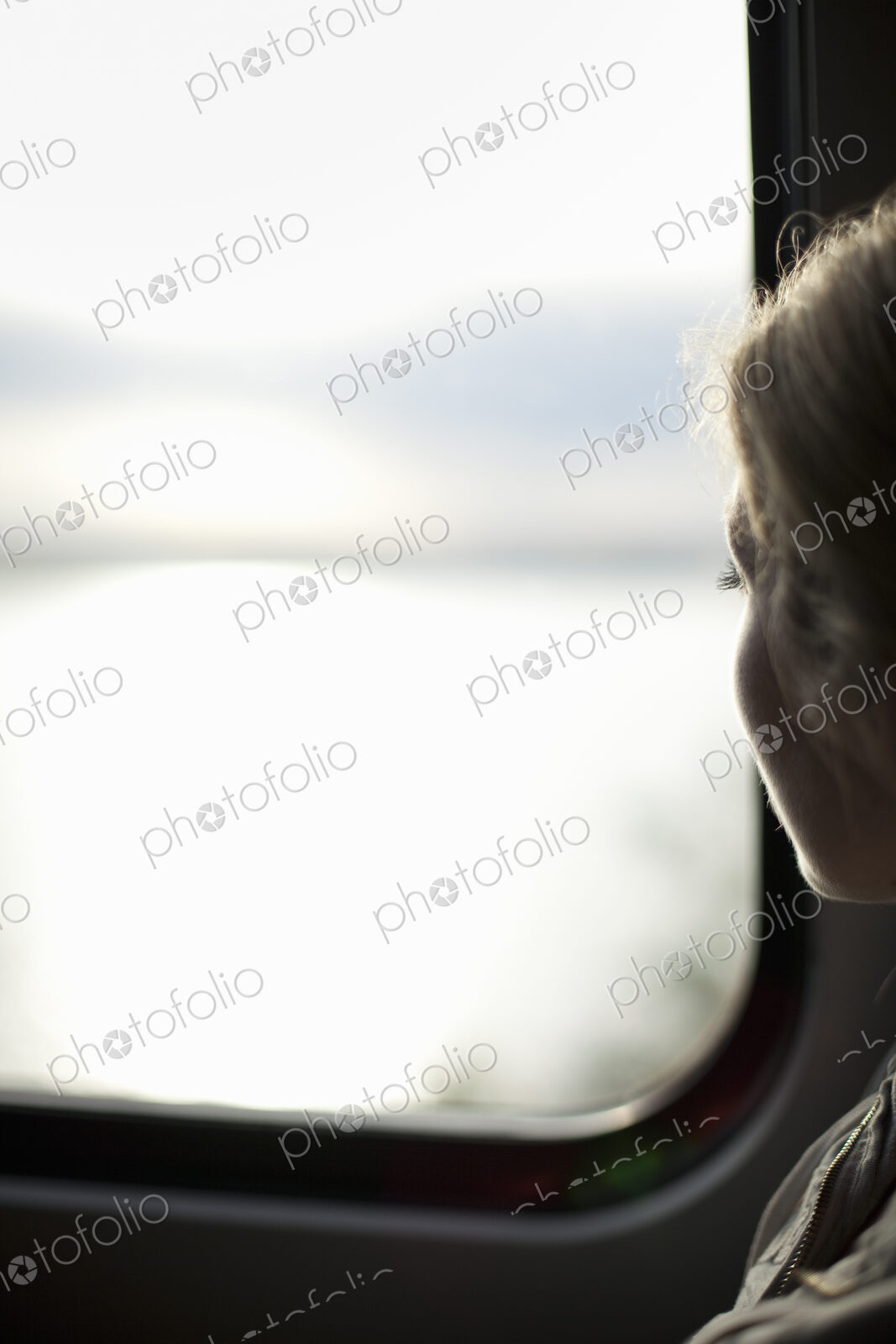 A woman sitting by a train window looking out at the view.