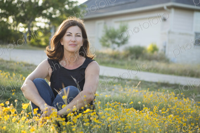 A woman sitting cross legged on the ground.