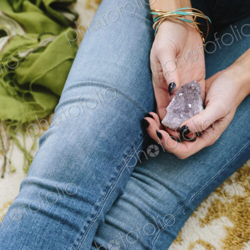 A woman sitting holding a small purple crystal in her hands. A woman sitting holding a small purple crystal in her hands.