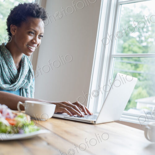 A woman sitting in a cafe with a cup of coffee and a meal. Using a laptop. A woman sitting in a cafe with a cup of coffee and a meal. Using a laptop.