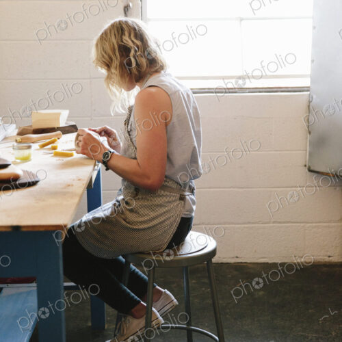 A woman sitting on a stool in a workshop.