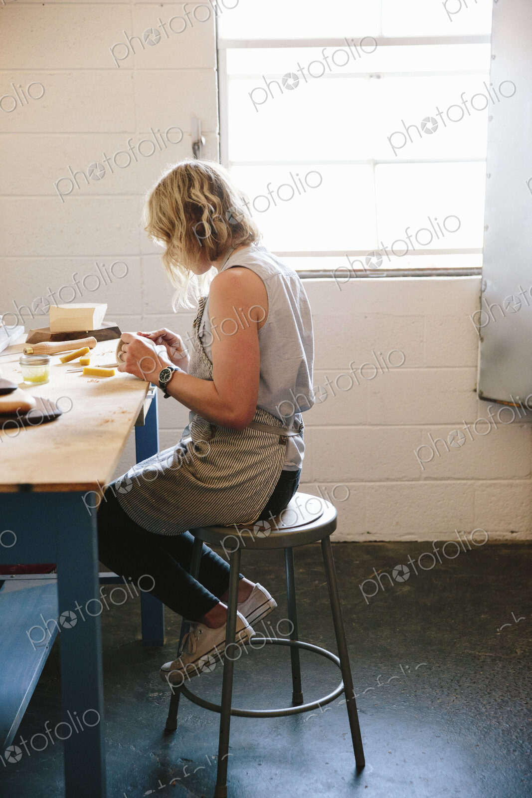 A woman sitting on a stool in a workshop.