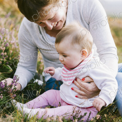 A woman sitting on the ground holding a young baby girl.