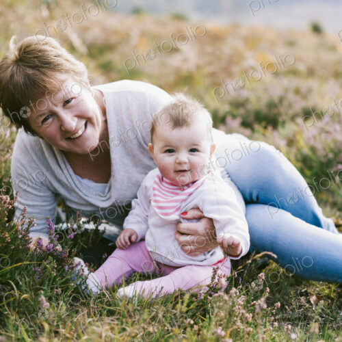 A woman sitting on the ground holding a young baby girl.