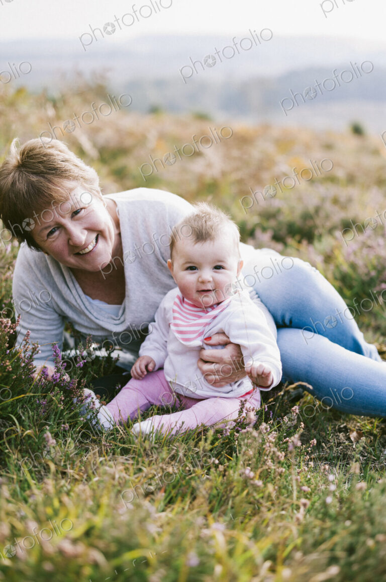 A woman sitting on the ground holding a young baby girl.