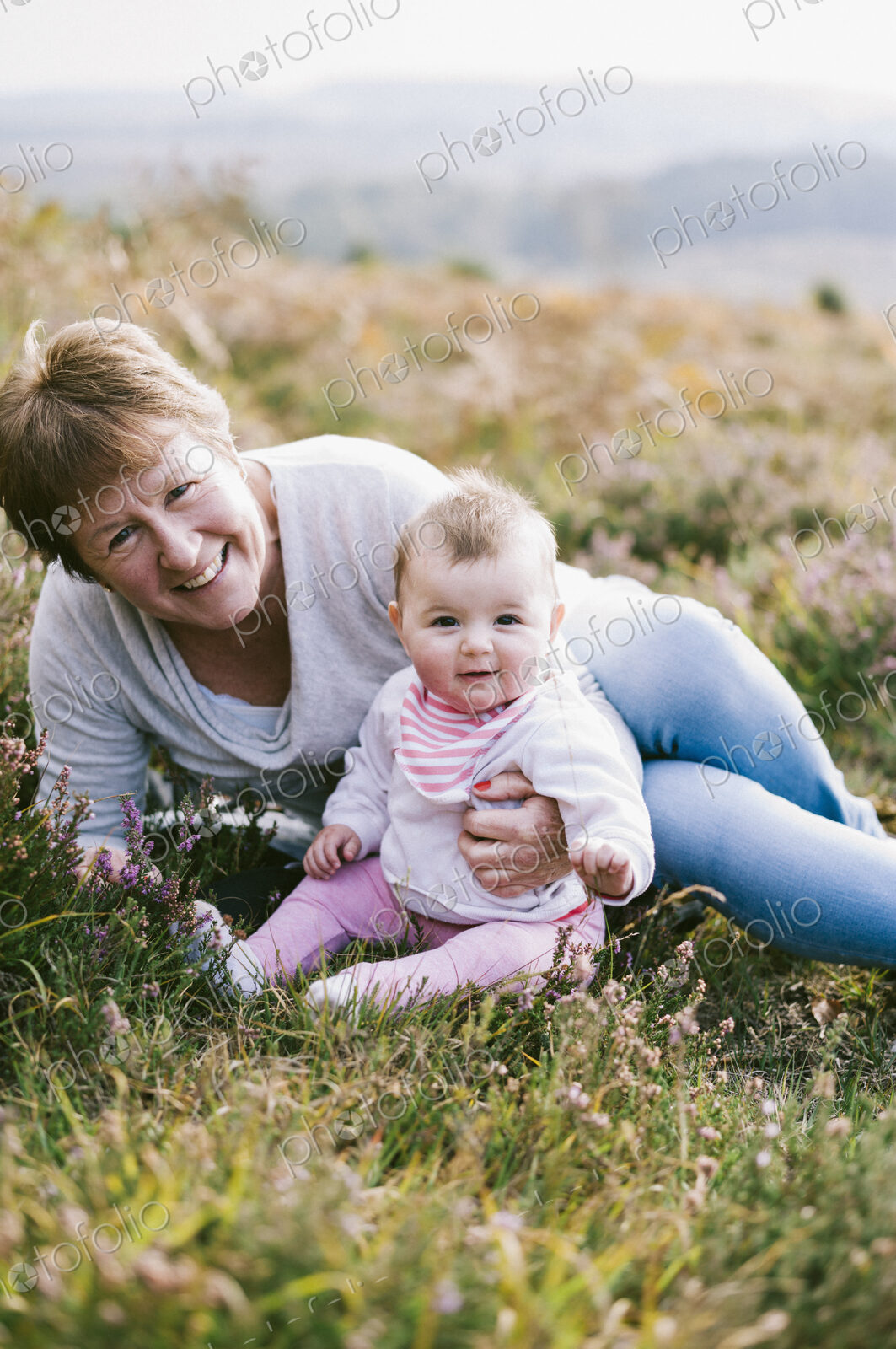 A woman sitting on the ground holding a young baby girl.