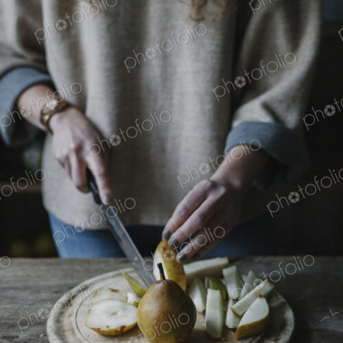 A woman slicing fresh fruit, pears.