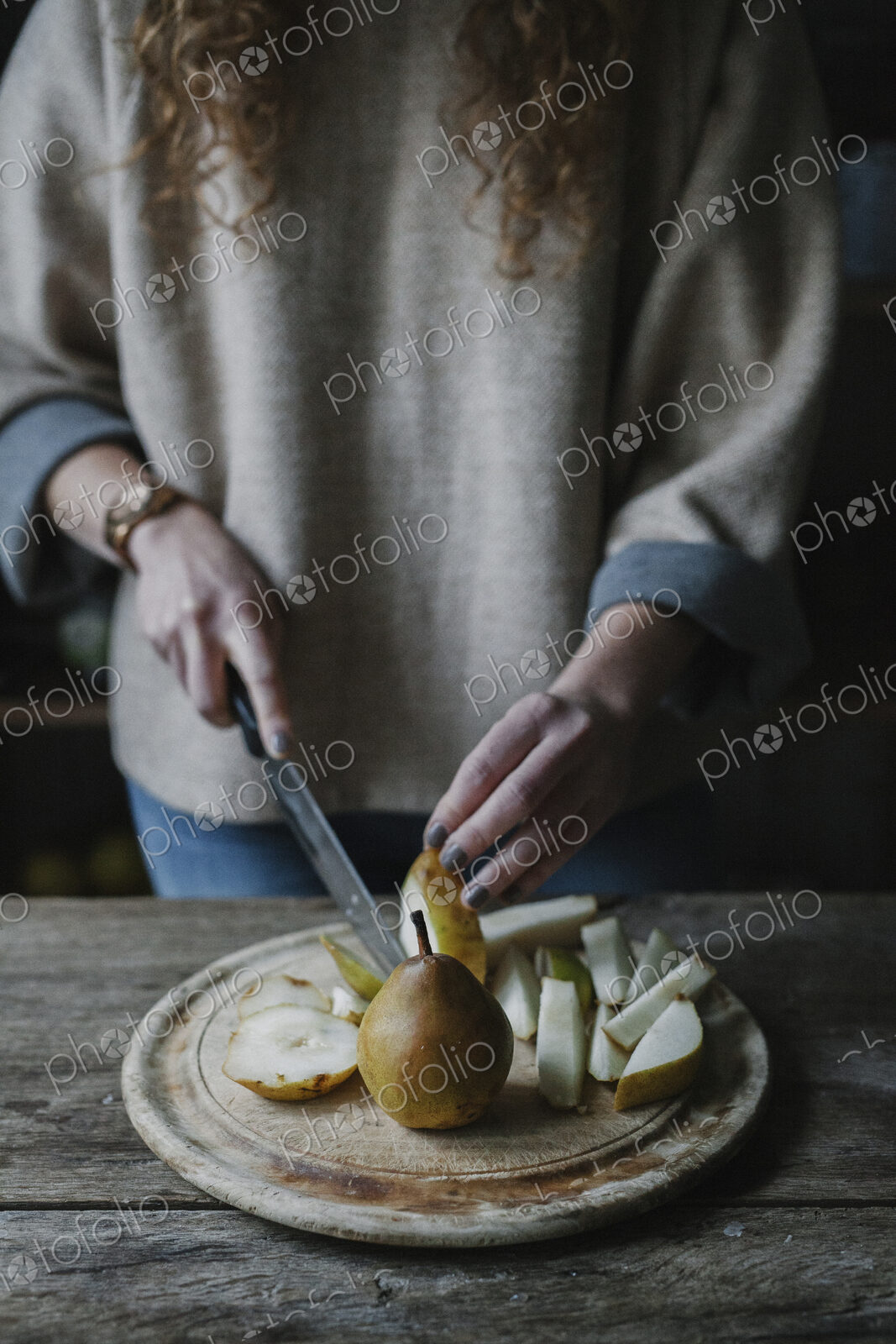 A woman slicing fresh fruit, pears.