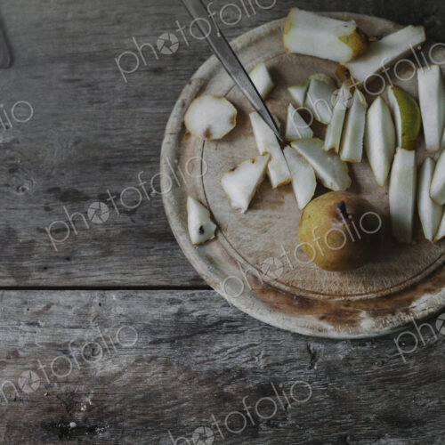 A woman slicing fresh fruit, pears on a chopping board.