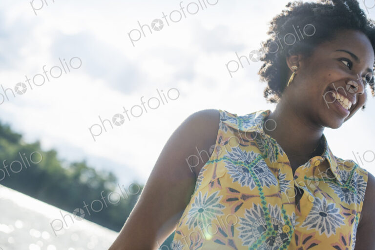 A woman smiling and laughing on a lake shore.