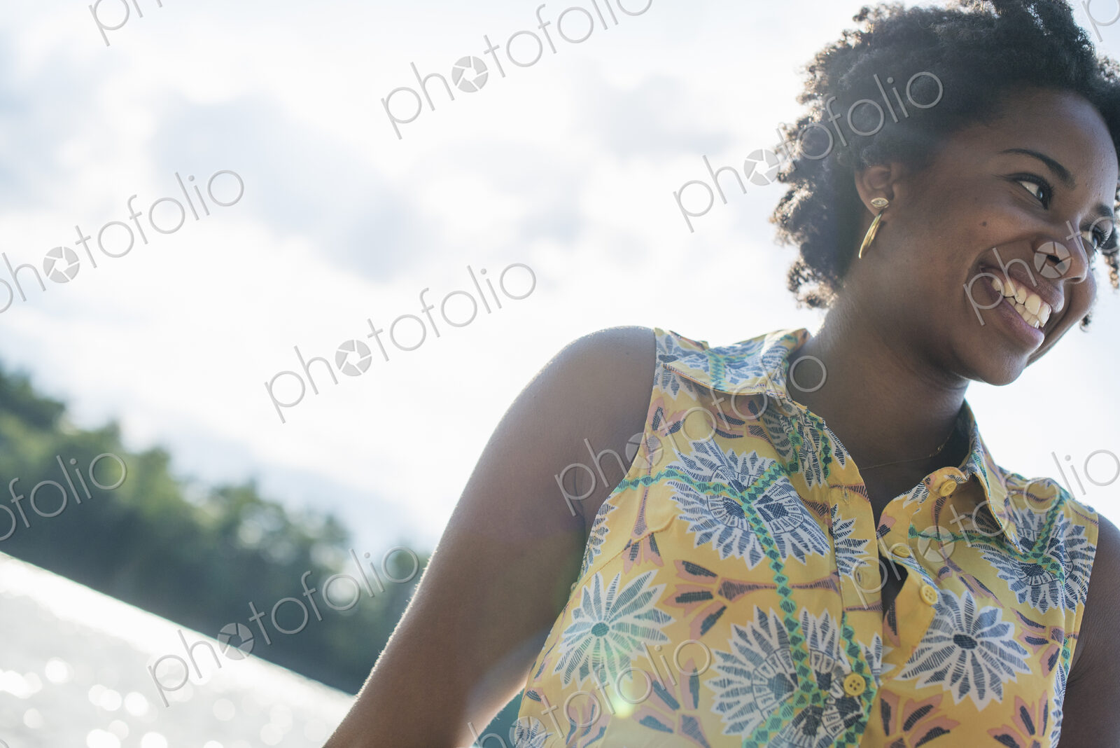 A woman smiling and laughing on a lake shore.