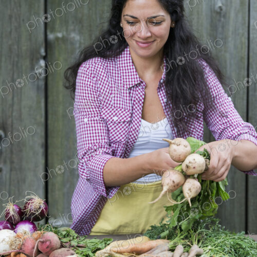A woman sorting freshly picked vegetables on a table. A woman sorting freshly picked vegetables on a table.