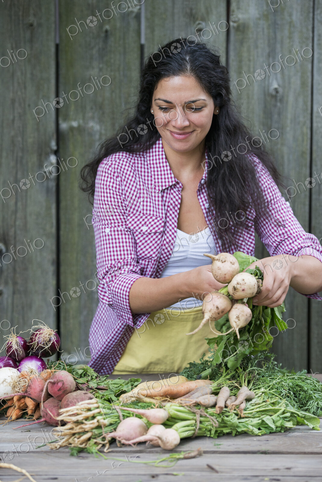 A woman sorting freshly picked vegetables on a table.