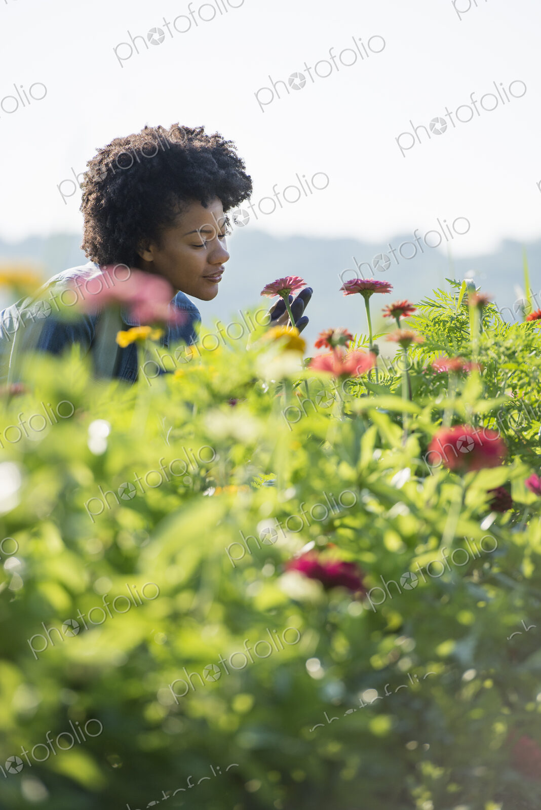 A woman standing among the flowers growing in the fields.