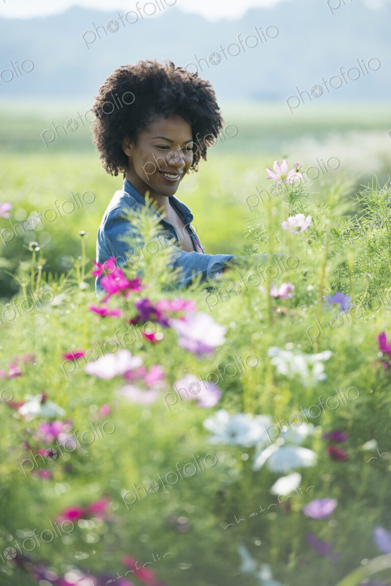 A woman standing among the flowers growing in the fields.