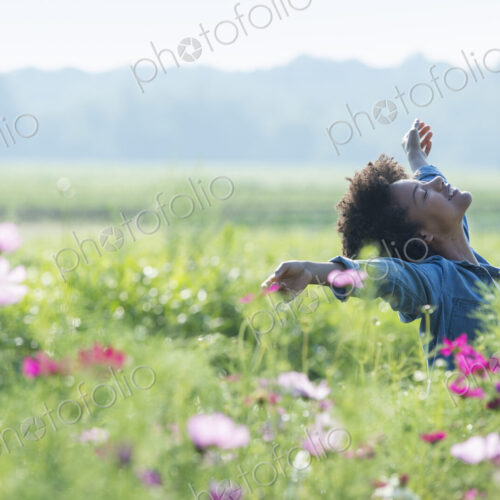 A woman standing among the flowers with her arms outstretched. Pink and white cosmos…