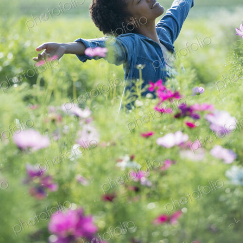 A woman standing among the flowers with her arms outstretched. Pink and white cosmos…
