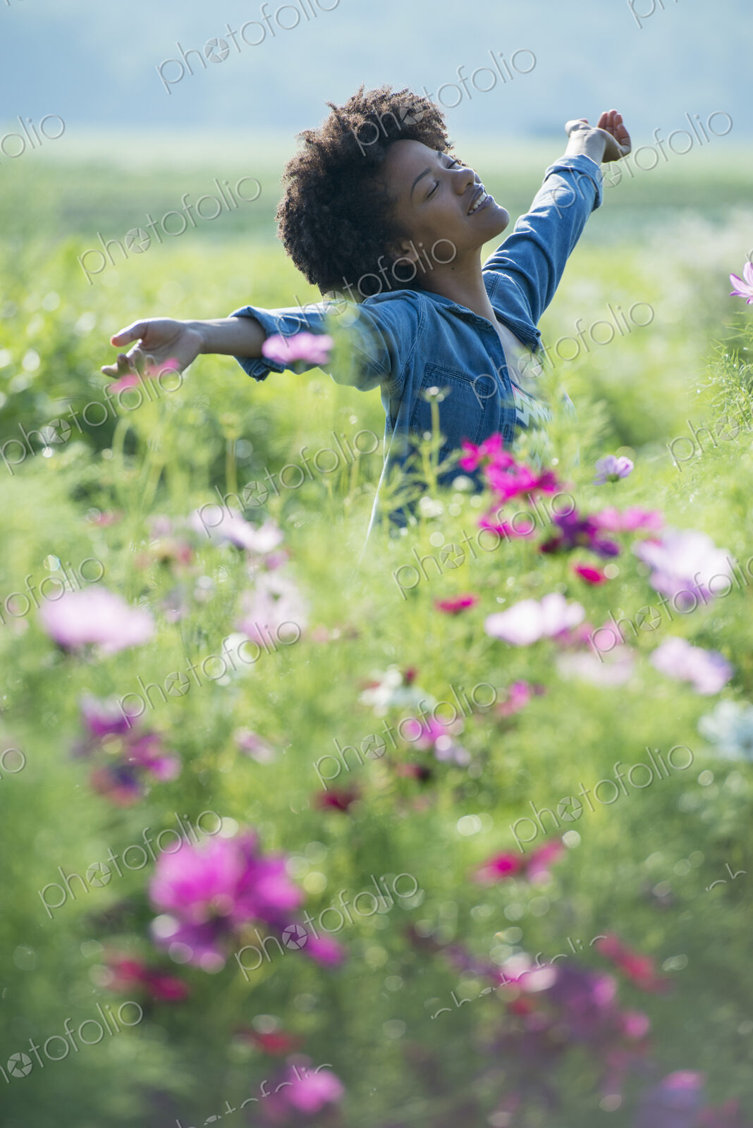 A woman standing among the flowers with her arms outstretched. Pink and white cosmos…
