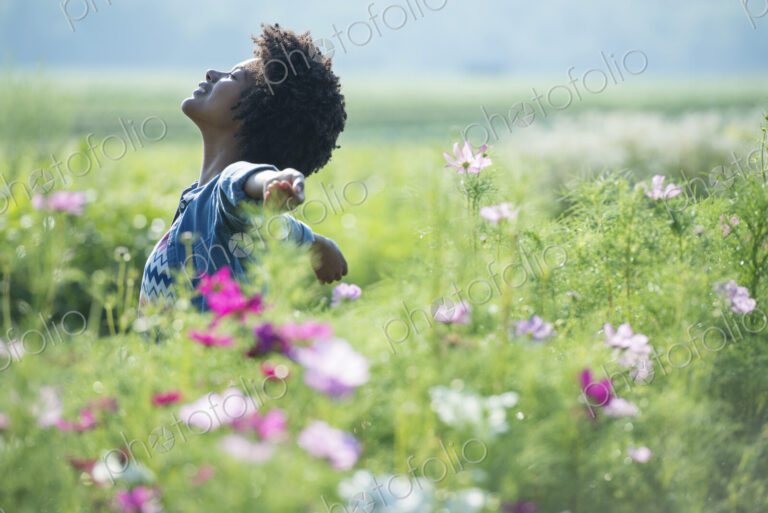 A woman standing among the flowers with her arms outstretched. Pink and white cosmos…