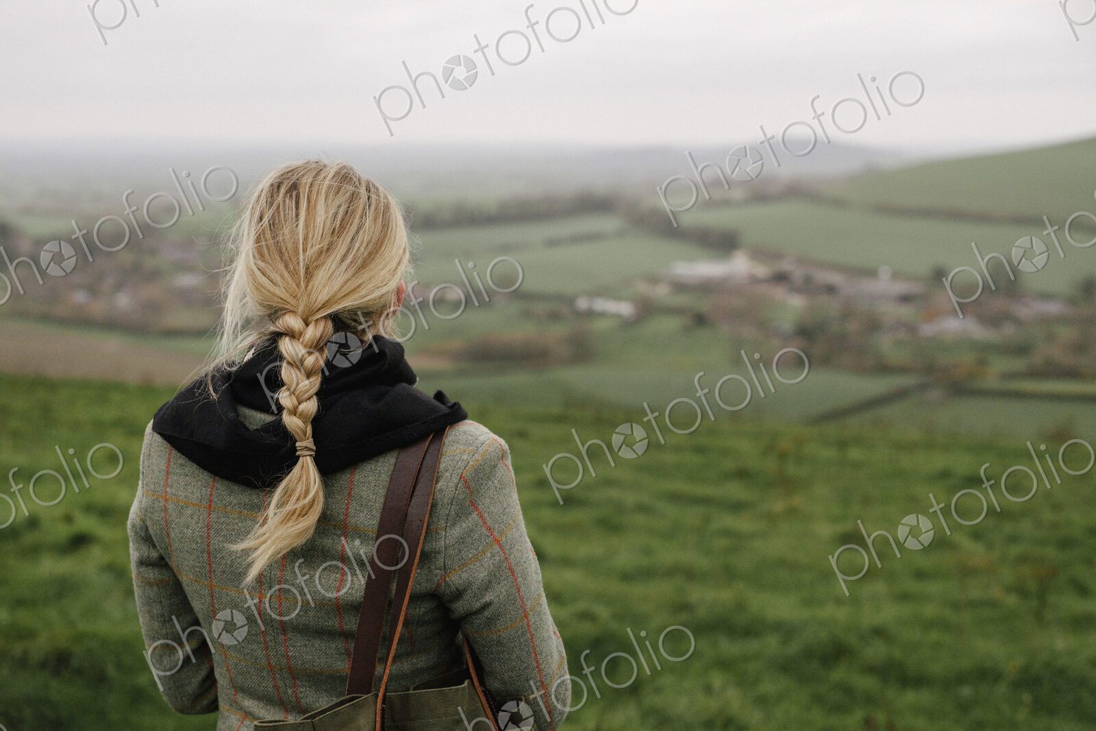 A woman standing in a hilltop looking at the view.