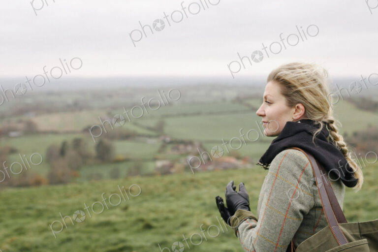 A woman standing in a hilltop looking at the view.