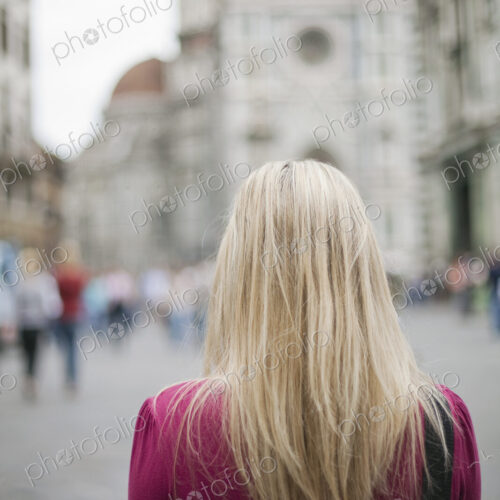 A woman standing in a square among the historic buildings of the city of Rome.