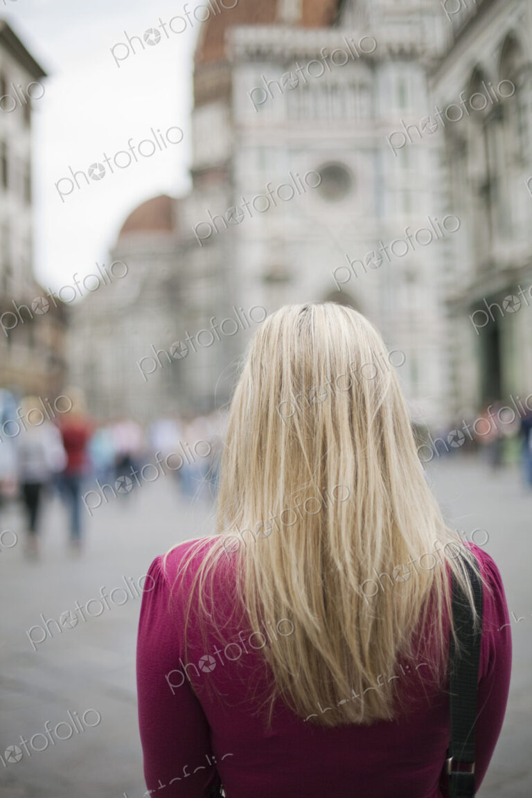 A woman standing in a square among the historic buildings of the city of Rome.