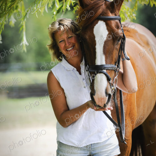 A woman standing next to a bayhorse with a halter rein. A woman standing next to a bayhorse with a halter rein.