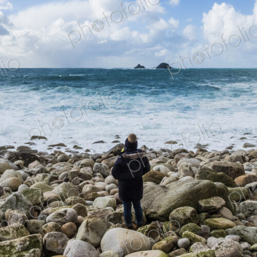 A woman standing on the rocks looking out over the Cornish coastline, and breaking waves. A woman standing on the rocks looking out over the Cornish coastline, and breaking waves.