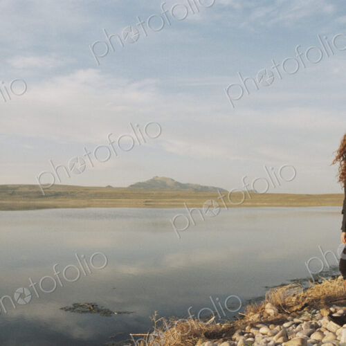 A woman standing on the shore of a lake.