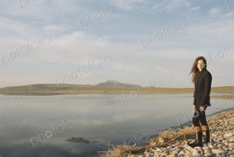A woman standing on the shore of a lake.