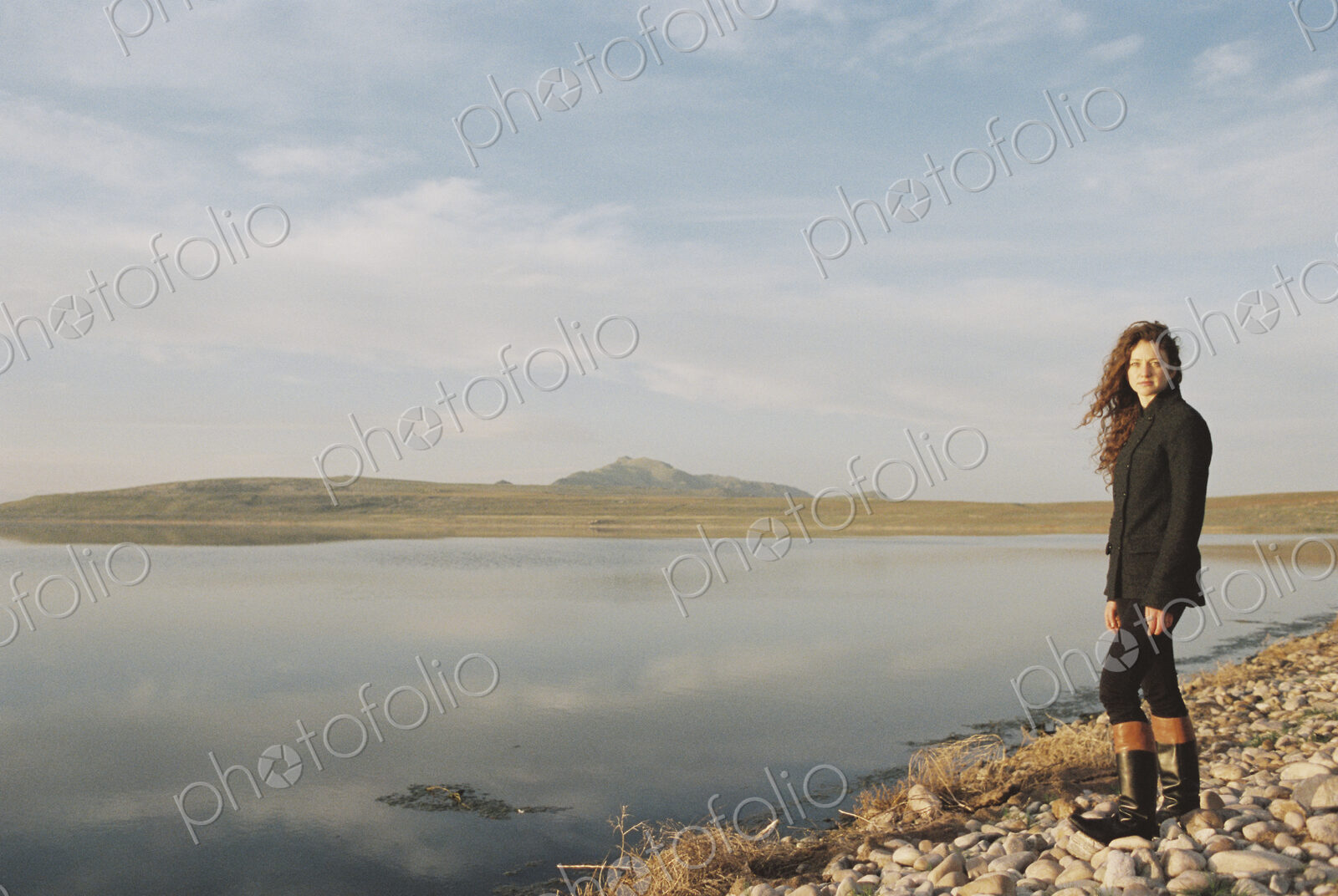 A woman standing on the shore of a lake.