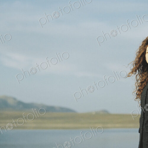 A woman standing on the shore of a lake. A woman standing on the shore of a lake.