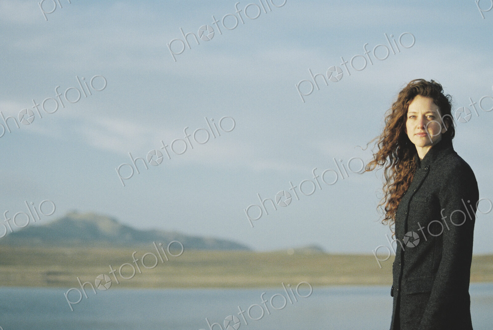 A woman standing on the shore of a lake.