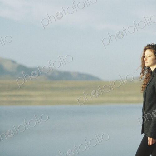 A woman standing on the shore of a lake.