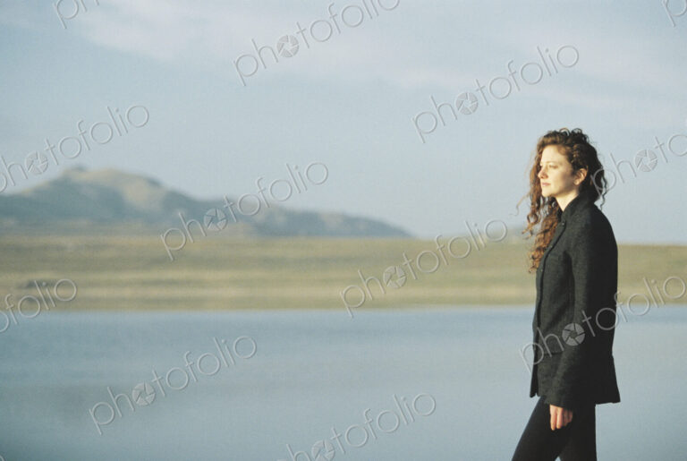 A woman standing on the shore of a lake.