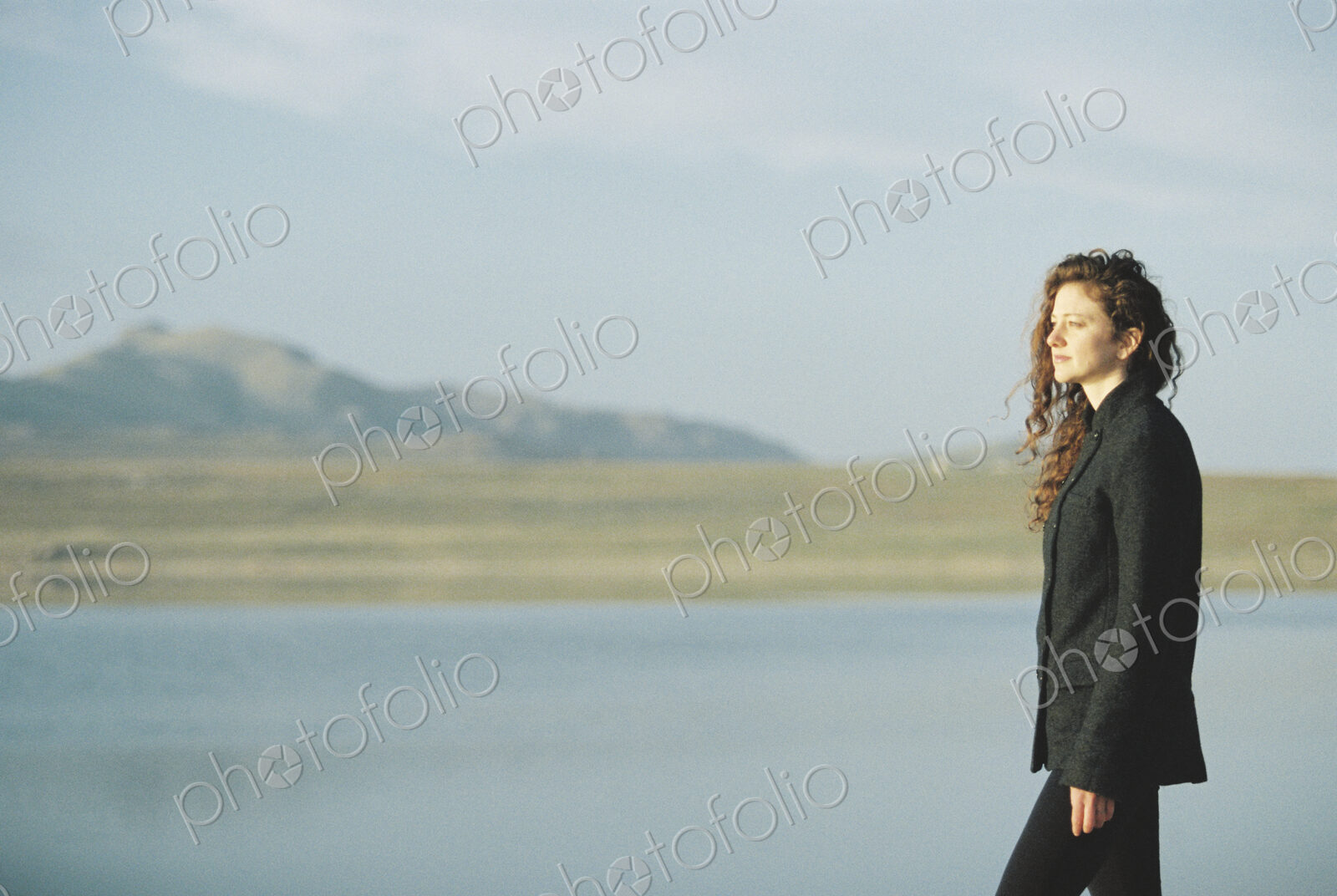 A woman standing on the shore of a lake.