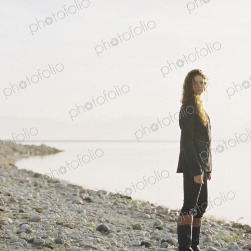 A woman standing on the shore of a lake.