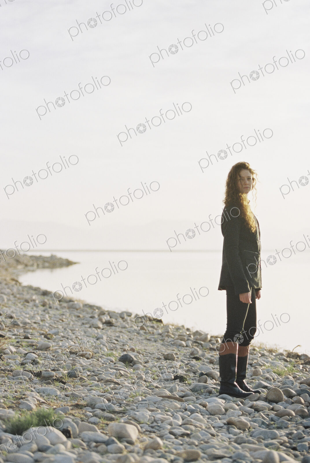 A woman standing on the shore of a lake.