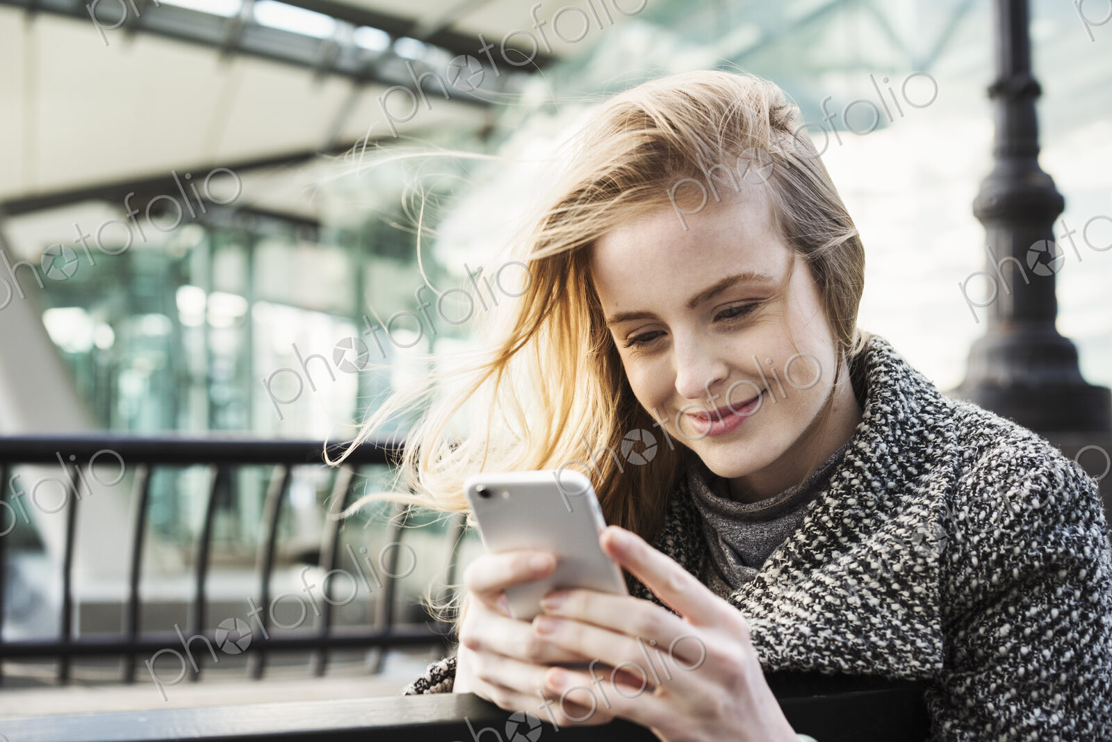 A woman standing outdoors in the city, checking her smart phone.