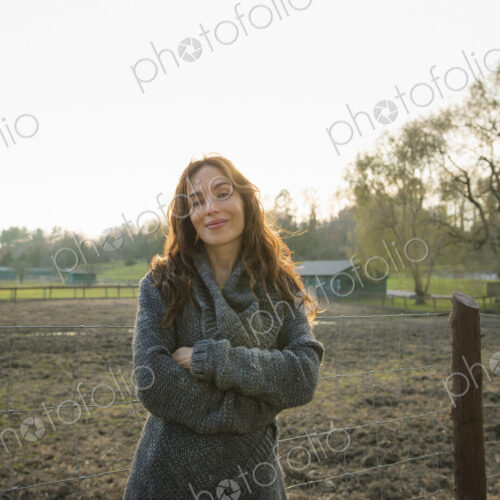 A woman standing with arms folded, by a paddock in an animal sanctuary. A woman standing with arms folded, by a paddock in an animal sanctuary.