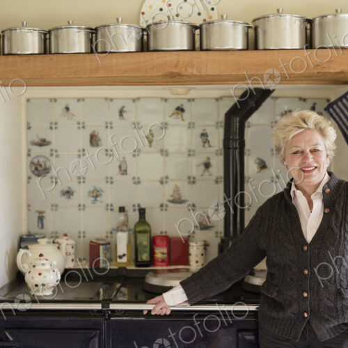 A woman standing with her back to a range cooker, in her kitchen. A woman standing with her back to a range cooker, in her kitchen.