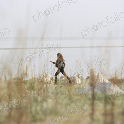 A woman striding across the grass past rocks along the shore of a lake. A woman striding across the grass past rocks along the shore of a lake.